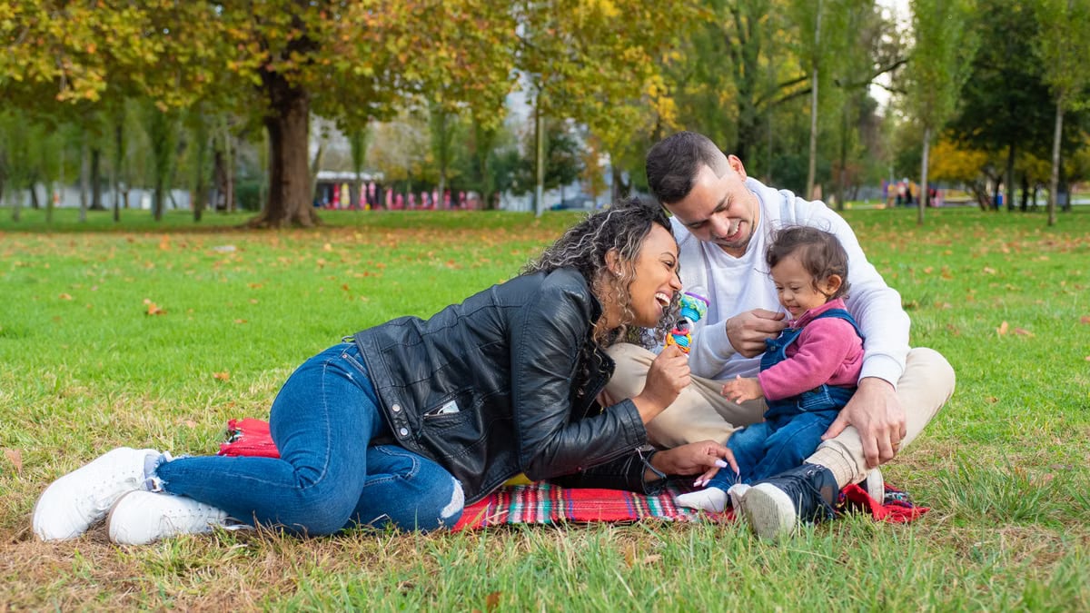 A cheerful family bonding outdoors while playing on a grassy field during autumn.